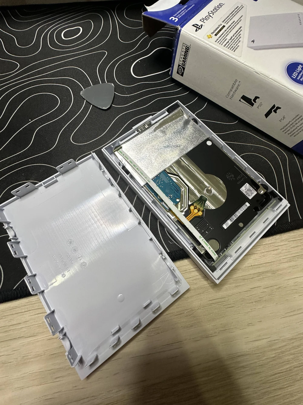 The enclosure pried open, the cover removed, revealing the drive inside